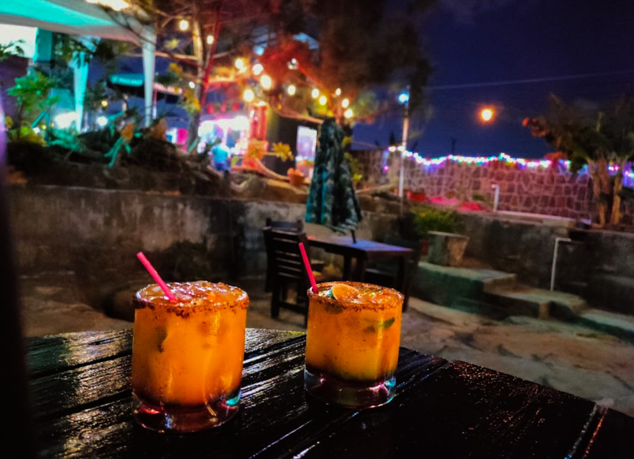 Dos cócteles artesanales con chile en la mesa de la terraza nocturna.